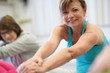 © goodluz - Portrait of senior woman in fitness class exercising on floor