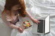 © Wavebreak Media - Woman using laptop while having breakfast in bedroom