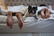 © Wavebreak Media - Couple lying on bed with their pet dog in bedroom