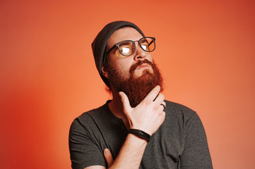 Wall Mural - Bearded man with eyeglasses touching his beard and looking away, studio shot