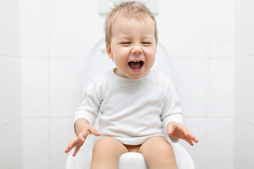 Wall Mural - Adorable young child sitting on the toilet