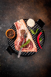 Fototapeta Mapy - Raw beef marbled meat striplon rib eye steak with spices, grill pan, and herbs, dark background top view, copy space