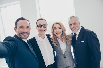 Self portrait of attractive, cheerful, stylish, confident business persons hugging, embracing, standing in workplace, workstation, shooting selfie, having break, pause, time out