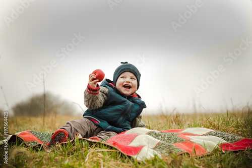 Plakat Dziecko śmieje się na pikniku i je pyszne jabłko
