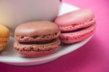 Wall Mural - assortment of french macarons pastry and cupof coffeee on pink background