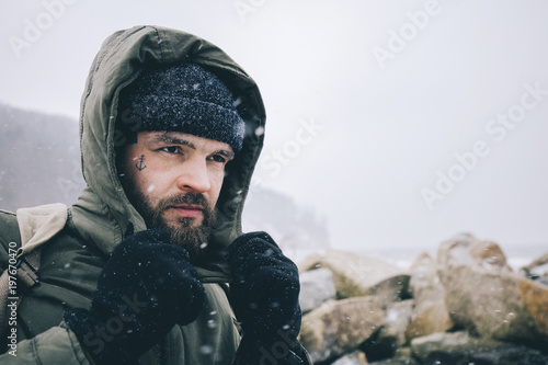 Man wearing warm clothing at beach during snowfall