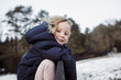 © Cavan Images - Portrait of smiling girl hanging on fence against sky during winter