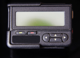 Black old pager or beeper isolated on black background 