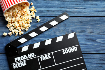 Clapperboard and popcorn on wooden background