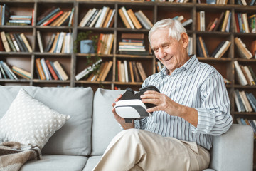 Wall Mural - Senior man at home retirement concept sitting holding virtual reality headset