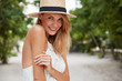 © WHstudio Leushin N - Happy delighted woman has pleasant appealing appearance, wears summer hat and white dress, has stroll on street, enjoys vacations or day off. Pretty young green eyed glad female model poses outdoor