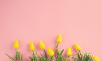 Canvas Print - Easter background. Bright yellow eggs and vivid spring blooming tulip flowers and fresh grass over pink background. Easter backdrop