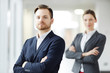 © pressmaster - Cross-armed young businessman and his colleague in suits looking at camera