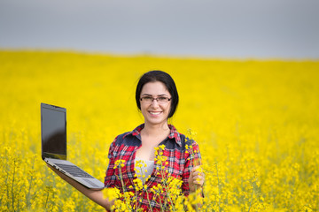 Wall Mural - Farmer woman with laptop in rapeseed field