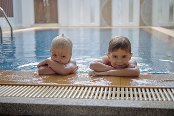 Two brothers preschool age, pool and house background