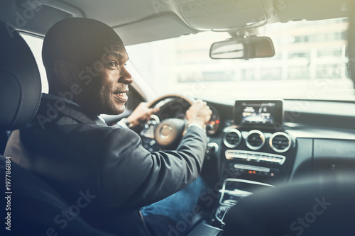 Fotomural Smiling young African man driving through the city