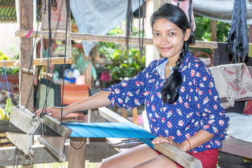 Wall Mural - young woman working at home on a weaving loom, Laos countryside.