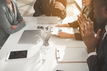 Canvas Print - Group of people sitting at office table with notebooks and pads while talking