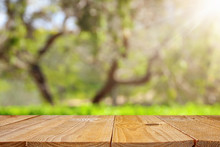Empty Rustic Table In Front Of Green Spring Abstract Bokeh Background. Product Display And Picnic Concept.