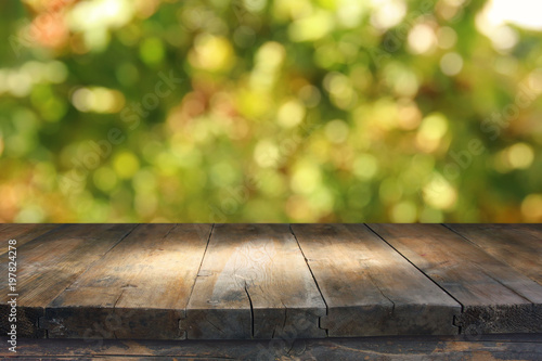 Zdjęcie XXL Pusty wieśniaka stół przed zielonej wiosny bokeh abstrakcjonistycznym tłem. wyświetlacz produktu i piknik.
