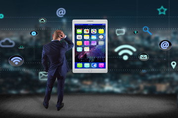 Poster - Businessman in front of a wall with a tablet surrounding by app and social icon - 3d render