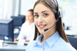 © ty - Beautiful young female call center operator with headset in office.