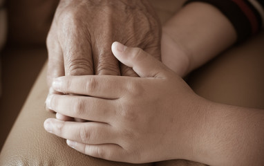 Wall Mural - Hands of little Asian kids holding poor elderly grandfather man hands wrinkled skin with feeling care and Love. World Kindness Day concept and Adult day care center, Family Older people concept