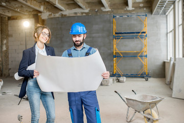 Wall Mural - Foreman expertising the structure with businesswoman holding a blueprints at the construction site indoors