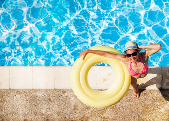 Wall Mural - Smiling woman in hat with rubber ring by the pool