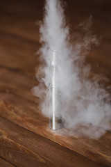 Electronic cigarette on a wooden table. Smoke.