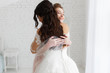 © oksana_bondar - luxury bride hugging bridesmaid and smiling, joyful moment in minimalistic loft white brick background
