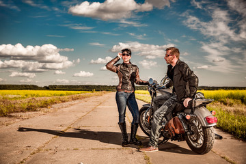 Wall Mural - Bikers couple Man and woman near a motorcycle on the road