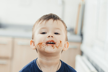 Charming child portrait, dirty face in chocolate or condensed milk