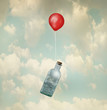 Surreal image representing a glass bottle with a stormy sea inside carried by a red balloon flying in the clouds