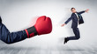 Big red boxing glove knocks out little businessman concept
