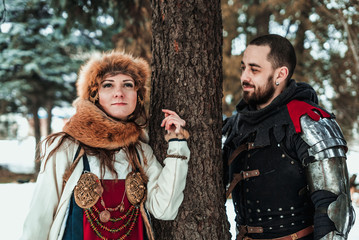 a man and a woman in historical costumes stand near a tree