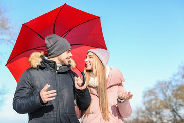 Wall Mural - Young romantic couple with bright umbrella on sunny winter day