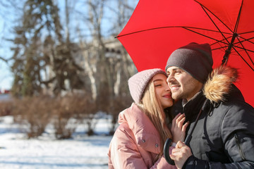 Poster - Young romantic couple with bright umbrella on sunny winter day