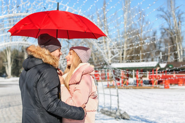 Poster - Young romantic couple with bright umbrella on sunny winter day