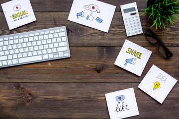 Work in social media. Media marketing. Desk with keyboard and socail media icons. Dark wooden background top view copy space