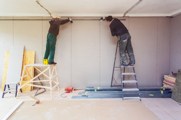 Wall Mural - Workers are installing plasterboard drywall for gypsum walls in apartment is under construction, remodeling, renovation, extension, restoration and reconstruction.