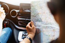 Hipster man holding in male hands and looking on navigation map in auto, tourist traveler hiker driving on background view way road, trip in transportation, person sitting on backdrop window auto