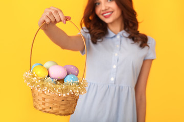 Wall Mural - Young woman studio isolated on yellow holding basket with eggs close-up