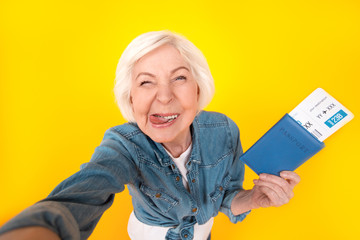 Senior woman traveler studio isolated on yellow wall taking selfie pictures top view