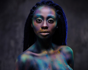 African woman with colourful powder on her face and body.