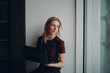 © primipil - Young beautiful blond student girl with laptop sitting at big window