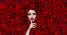 Portrait Of A Beautiful Young Girl In Red Rose Petals. Red Lips, Red Fingernails. The Girl Makes A Gesture With Her Hand.Fashion, Beauty, Make-up, Cosmetics, Hairstyle, Beauty Salon, Boutique, Discoun