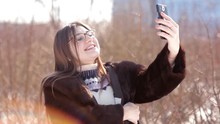 Beautiful Girl In A Snow-covered Winter City Using Skype On A Smartphone Communicates With His Family