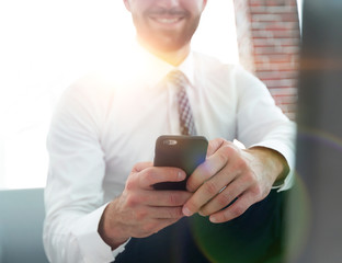 Canvas Print - businessman holding a smartphone and looking at the camera