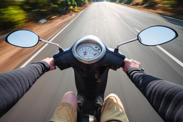 Rider driving scooter on an asphalt road. Motion blurred backgro